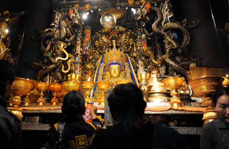 People pray in front of a figure of buddha at Jokhang Temple in Lhasa, southwest China's Tibet Autonomous Region, while celebrating the peak day of the Sakadawa Festival, June 7, 2009. The Sakadawa Festival, which falls on the First Day of the Fourth Month of the Tibetan Calendar, is celebrated by Tibetan Buddhists to commemorate Sakyamuni's birth, enlightenment and death. [Gesang Dawa/Xinhua] 