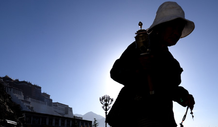 A faithful prays in front of Potala Palace in Lhasa, southwest China's Tibet Autonomous Region, while celebrating the peak day of the Sakadawa Festival, June 7, 2009. [Gesang Dawa/Xinhua]