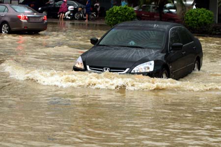A car wades through a flooded street in the downtown of Zhanjiang, south China's Guangdong Province, June 7, 2009. The city of Zhanjiang has been heavily inundated after being hit by a heavy rainstorm, leaving the traffic in difficulty.[Zhou Long/Xinhua]