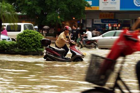  Pedestrians and vehicles wade through a flooded street in the downtown of Zhanjiang, south China's Guangdong Province, June 7, 2009. The city of Zhanjiang has been heavily inundated after being hit by a heavy rainstorm, leaving the traffic in difficulty.[Zhou Long/Xinhua]