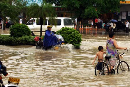 Pedestrians and vehicles wade through a flooded street in the downtown of Zhanjiang, south China's Guangdong Province, June 7, 2009. The city of Zhanjiang has been heavily inundated after being hit by a heavy rainstorm, leaving the traffic in difficulty.[Zhou Long/Xinhua]