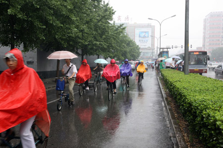 People ride bicycles in rain in Beijing, June 8, 2009. It rains in Beijing on Monday. [Gao Xueyu/Xinhua] 