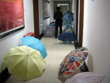 A working staff passes by umbrellas in a building in Beijing, June 8, 2009. [Zhang Yanhui/Xinhua]