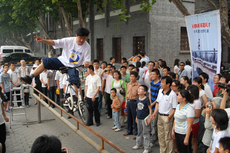 A folk stunt performer shows acrobatic skill of riding bicycle on the steel tube, during the Traditional Chinese Folk Stunts Show, on the Xijindu Ancient Street of Zhenjiang City, east China's Jiangsu Province, June 7, 2009. The folk artists from around the country put on myriad of traditional Chinese folk stunt shows, to mark the 4th Cultural Heritage Day of the country, which falls on June 13th. [Chen Gang/Xinhua]