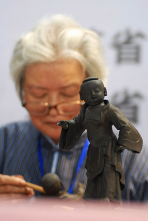 A folk handicraftsman extemporizes the craftwork, during the Traditional Chinese Folk Stunts Show, on the Xijindu Ancient Street of Zhenjiang City, east China's Jiangsu Province, June 7, 2009. [Chen Gang/Xinhua]