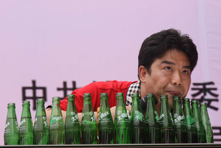 A folk stunt performer shows unique skill of blowing the beverage bottles for music melody, during the Traditional Chinese Folk Stunts Show, on the Xijindu Ancient Street of Zhenjiang City, east China's Jiangsu Province, June 7, 2009. [Chen Gang/Xinhua]