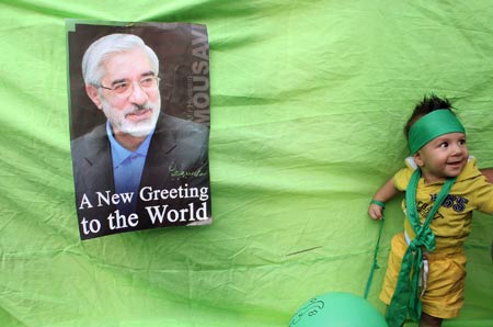 A little boy stands beside a poster of Iranian presidential hopeful Mir Hossein Mousavi, former Prime Minister, during a presidential election campaign in Teheran, capital of Iran, June 8, 2009. Thousands of backers of Mousavi formed a human chain here on Monday to support him in the presidential elections on June 12. [Ahmad Halabisaz/Xinhua]