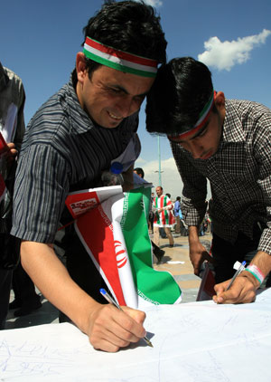 Two supporters of Iranian President Mahmoud Ahmadinejad sign on a scroll during a presidental election campaign in Teheran, capital of Iran, June 8, 2009. Tens of thousdands of Mahmoud Ahmadinejad's supporters held a rally here on Monday, supporting the incumbent hardliner Mahmoud Ahmadinejad to grasp the second four-year term in the presidential elections on June 12. [Liang Youchang/Xinhua]