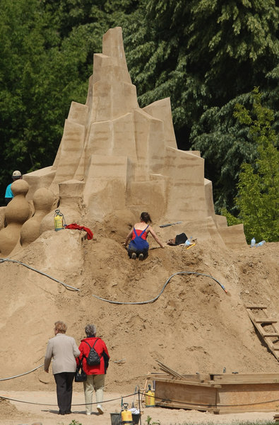  Visitors watch an artist work on a sand sculpture at the 7th Sandsation international sand sculpture festival on June 8, 2009 in Berlin, Germany. Sandsation runs through August 30 and has attracted artists from all over the world. [CFP]