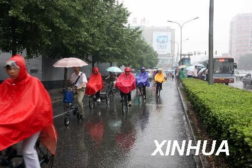 People ride bicycles in rain in Beijing, June 8, 2009. It rains in Beijing on Monday. 