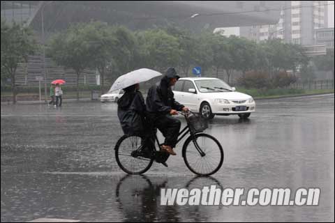 People ride a bicycle in rain in Beijing, June 8, 2009. It rains in Beijing on Monday. 
