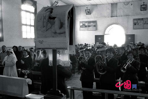 A pinup calendar lies draped over a lectern as the congregation sings hymns, Taibai county, June, 2001