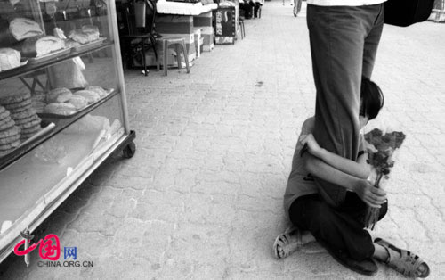 A child flower seller holds on to a pedestrian's leg, Shenzhen, 1996