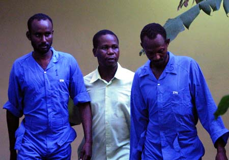 Two suspected Somali pirates are guarded by a Kenyan policeman (C) in the port city of Mombasa, east Kenya, on June 8, 2009. The Swedish Navy on Monday handed over to Kenya seven suspected pirates who were arrested on May 26 as they attacked a merchant vessel in the Gulf of Aden. [Xinhua]