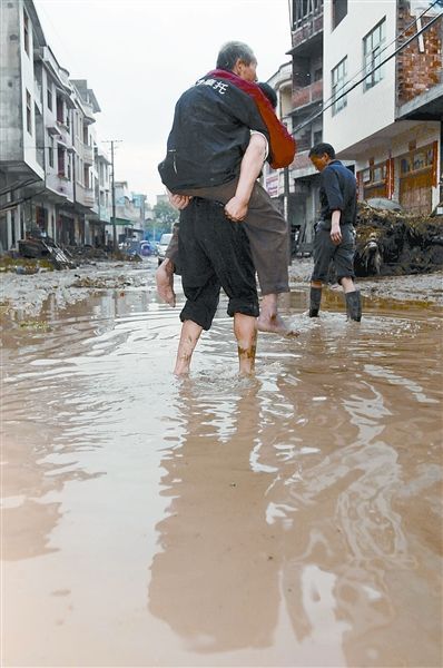 People wade through a flooded road in the downtown of Suining, central China's Hunan Province, June 9, 2009. [Hunan Daily]