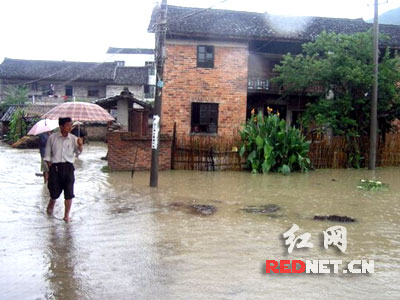 People wade through a flooded road in the downtown of Suining, central China's Hunan Province, June 9, 2009. 