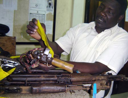 A Kenyan police officer inspects weapons of suspected Somali pirates in Mombasa, city of east Kenya, June 10, 2009. U.S. Navy handed over 17 suspected Somali pirates to Kenyan authorities on Wednesday against the backdrop of foreign warships stepping up naval patrols off the coast of Somalia. [Xinhua]