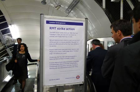 Commuters pass by a poster of an underground train strike at the Green Park tube station in London, June 9, 2009. [Zeng Yi/Xinhua]