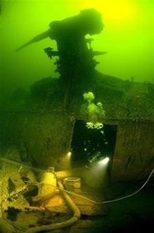 This undated image made available Tuesday, June 9, 2009 by Stefan Hogeborn, shows a diver examining the hull and deck gun of a Soviet submarine that sank with a crew of 50 during World War II. [Stefan Hogeborn/CCTV/AP Photo] 