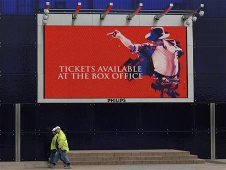 Workmen pass an advertising board for the forthcoming Michael Jackson concerts at the O2 Arena in London March 13, 2009. 
