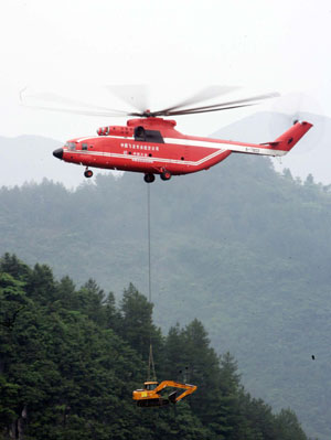 A MI-26 helicopter carries an excavator to the landslide site of Jiwei Mountain, in Wulong County, southwest China's Chongqing Municipality, June 11, 2009. The MI-26 heavy-lifting helicopter has begun carrying heavy machineries needed in the search for 63 people missing in a massive landslide on Friday. The heavy machineries will be used to remove giant rocks that buried two entrances to an iron ore mine, where 27 miners are believed to be trapped.[Chen Shan/Xinhua]