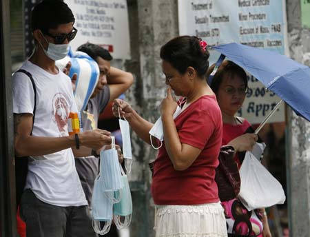 A woman buys face masks to a vendor on a busy street in Manila June 11, 2009. Health Secretary Francisco Duque III said on Thursday, 15 new cases of new flu virus were confirmed bringing the total number of Influenza A(H1N1) cases to 92, the highest number in southeast Asia. [Xinhua/Reuters]