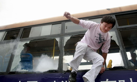 A bus company personnel escapes through broken window during an emergency drill in Shanghai, Thursday June 11, 2009, in the wake of a freak bus blaze in southwest China's Chengdu that killed 27 passengers, leaving another 63 injured. [Xinhua]