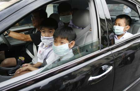 School boys wears masks as their parents drive them back home from a private school in Bangkok June 11, 2009. A Bangkok school will be partially closed from Thursday for three days after an 11-year-old boy came down with H1N1 flu in the second known case of local infection. Thirteen of his classmates have also developed fevers, local newspapers reported. [Xinhua/Reuters] 