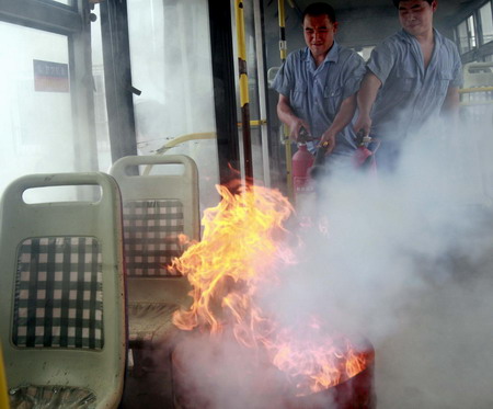 Bus company staff try to extinguish a fire during an emergency drill in Shanghai, Thursday June 11, 2009, in the wake of a freak bus blaze in southwest China's Chengdu that killed 27 passengers, leaving another 63 injured. [Xinhua]