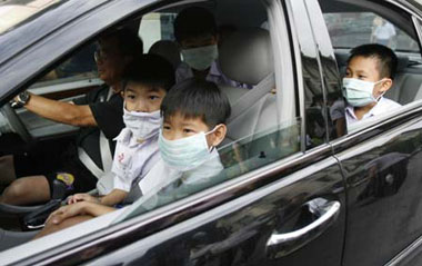 School boys wears masks as their parents drive them back home from a private school in Bangkok June 11, 2009. A Bangkok school will be partially closed from Thursday for three days after an 11-year-old boy came down with H1N1 flu in the second known case of local infection. Thirteen of his classmates have also developed fevers, local newspapers reported. [Xinhua/Reuters]