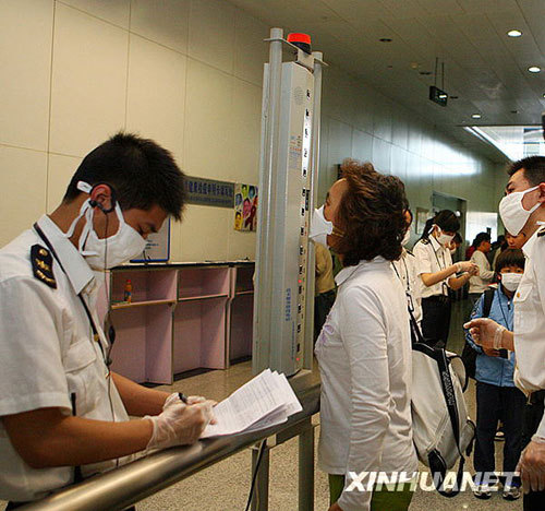 Passengers are asked to test their temperature in the Xianyang Airport, Shaanxi Province, on May 5, 2009. China promised to increase efforts to stem the A/H1N1 virus after the World Health Organization (WHO) raised the flu alert to its highest level on June 12.
