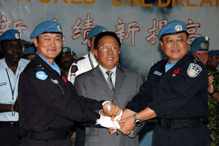 Zhang Daning (R), commissar of China's 7th riot police squad to Haiti on a peacekeeping mission for the United Nations, and Li Qin, commissair of 8th riot police squade to Haiti, holds a handover ceremony in Port-au-Prince, June 13, 2009. [Yin Nan/Xinhua]