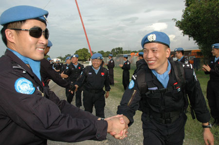 Chinese peacekeeping police (R) says adieu to their successor in Port-au-Prince, capital of Haiti, June 13, 2009. [Yin Nan/Xinhua]