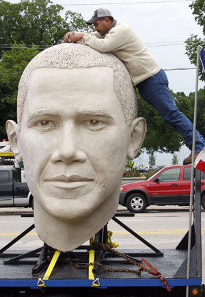 Jesse Flores, a worker for SculptureWorx Studio, stands on a railing as he fixes the top of an eight-foot-tall sculpture of the head of U.S. President Barack Obama on display in the Grant Park area of downtown Chicago, Illinois June 13, 2009.[Xinhua/Reuters] 