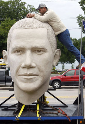 Jesse Flores, a worker for SculptureWorx Studio, stands on a railing as he fixes the top of an eight-foot-tall sculpture of the head of U.S. President Barack Obama on display in the Grant Park area of downtown Chicago, Illinois June 13, 2009.[Xinhua/Reuters]