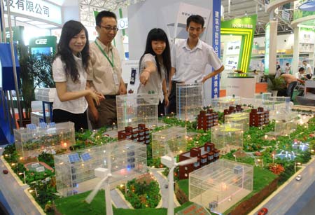 Visitors are attracted by a model of comprehensive new energy source utilizing system at the China International Energy Saving and Environmental Protection Exhibition 2009 in Beijing, capital of China, June 14, 2009. The exhibition kicked off on Sunday and attracted over 250 enterprises from home and abroad. [Xinhua]