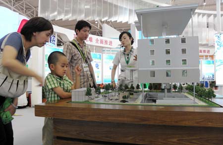 Visitors are attracted by a model of energy saving building at the China International Energy Saving and Environmental Protection Exhibition 2009 in Beijing, capital of China, June 14, 2009. The exhibition kicked off on Sunday and attracted over 250 enterprises from home and abroad. [Xinhua]