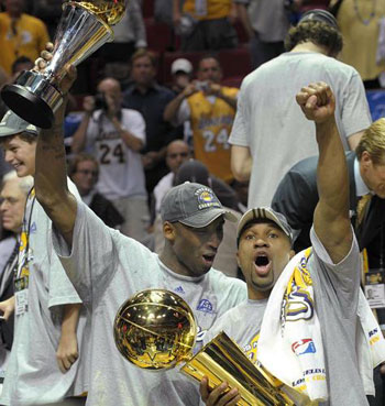 Los Angeles Lakers' Kobe Bryant (L) holds the MVP trophy as teammate Derek Fisher holds the Larry O'Brien Championship trophy after the Lakers beat the Orlando Magic in Game 5 of their NBA Finals basketball game in Orlando, Florida June 14, 2009.[Xinhua]