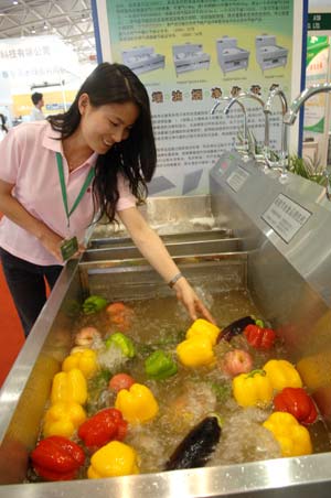 A worker shows a highly-efficient food cleaning system at the China International Energy Saving and Environmental Protection Exhibition 2009 in Beijing, capital of China, June 14, 2009. The exhibition kicked off on Sunday and attracted over 250 enterprises from home and abroad. [Xinhua] 