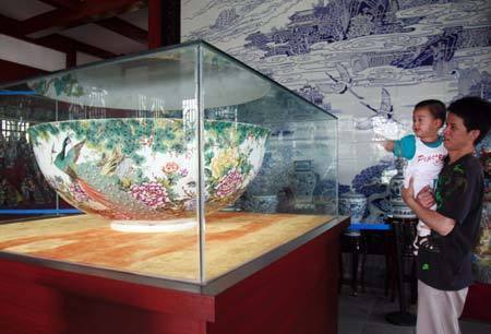 A man views a huge eggshell porcelain bowl displayed in Jiujiang, east China's Jiangxi Province, June 13, 2009. The huge bowl, with a diameter of 126 centimeters, has been finished in Jingdezhen last year. (Xinhua/Shen Junfeng) 