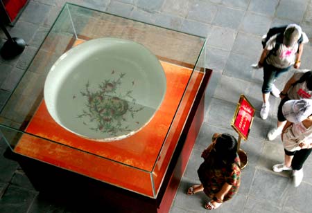 Visitors view a huge eggshell porcelain bowl displayed in Jiujiang, east China&apos;s Jiangxi Province, June 13, 2009. The huge bowl, with a diameter of 126 centimeters, has been finished in Jingdezhen last year. (Xinhua/Shen Junfeng)