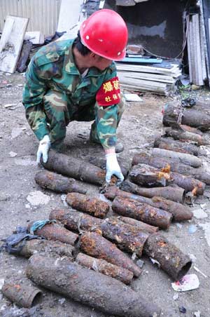 A worker counts shells abandoned by Japanese invading troops at a porcelain market in Mudanjiang, a city in northeast China's Heilongjiang Province, June 15, 2009. A total of 95 shells abandoned by Japanese invading troops were excavated in Mudanjiang on Monday. [Xinhua]