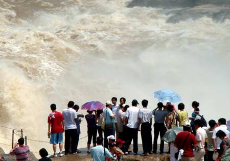 Sightseers view the spectacular torrential Hukou (Kettle Mouth) Waterfall on the Yellow River in Yichuan, northwest China's Shaanxi Province, June 14, 2009. [Xinhua]