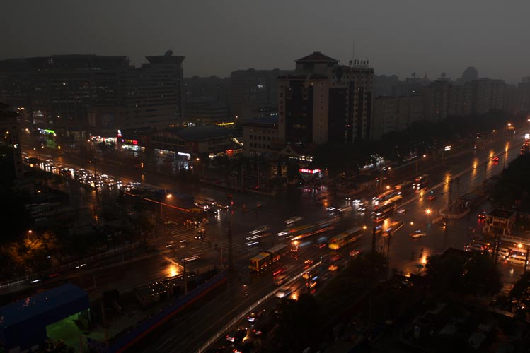 Vehicle lights and illumination of buildings were turned on as a heavy thunder storm hits Beijing Tuesday morning, causing darkness in the city during the daytime.[CFP]