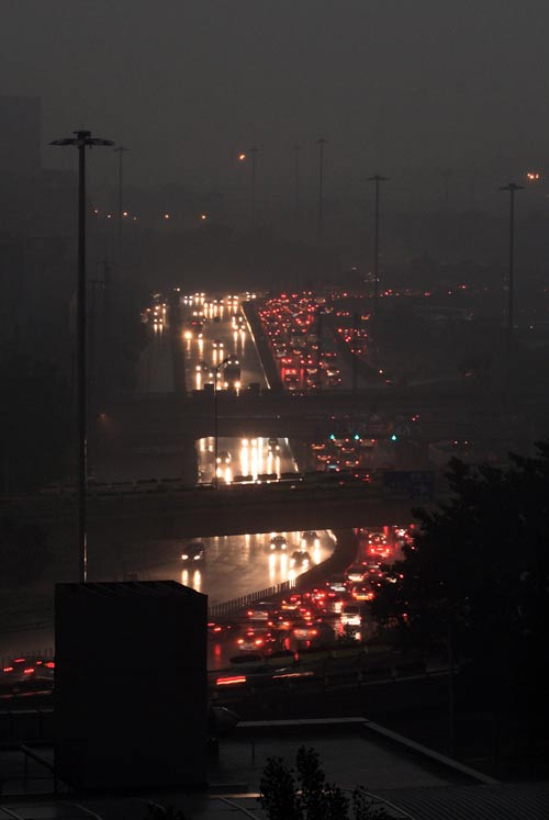 Vehicle lights and illumination of buildings were turned on as a heavy thunder storm hits Beijing Tuesday morning, causing darkness in the city during the daytime.[CFP]