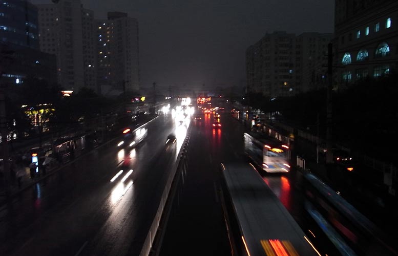 Vehicle lights and illumination of buildings were turned on as a heavy thunder storm hits Beijing Tuesday morning, causing darkness in the city during the daytime.[CFP]