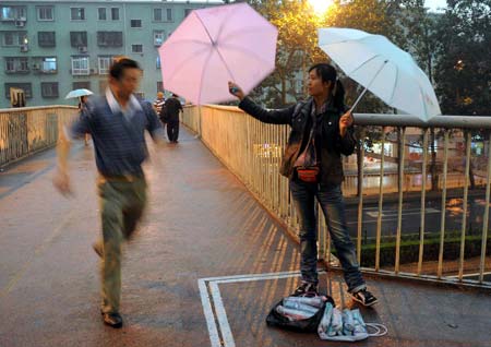 A vendor sells umbrellas in the rain in Beijing, China, June 16, 2009. Local authority released a yellow alert for lightings on Tuesday. [Luo Xiaoguang/Xinhua]