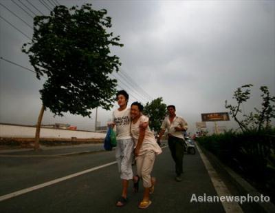Pedestrians walk on the road in strong winds in Hefei, east China's Anhui province Sunday, June 14, 2009. At least 14 people were killed and more than 180 others were injured in a severe hail storm that destroyed thousands of homes across east China's Anhui province, authorities have said. [CCTV/Asianewsphoto]