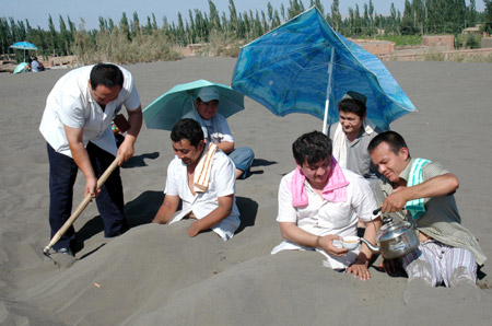 Several tourists undergo sand therapy in Turpan, northwest China's Xinjiang Uygur Autonomous Region, June 15, 2009.[Xinhua]