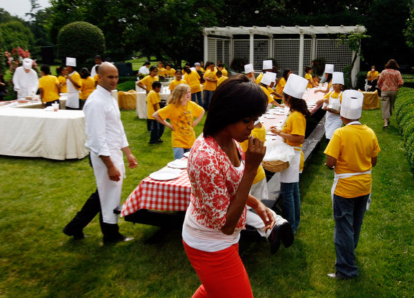 U.S. first lady Michelle Obama tastes a snap pea from the White House Kitchen Garden harvested with students from Bancroft Elementary School on the South Lawn of the White House June 16, 2009 in Washington, DC. The first lady then sat down to a meal with the children including the lettuce and snap peas harvested from the garden to focus attention on health and nutrition. [CFP]